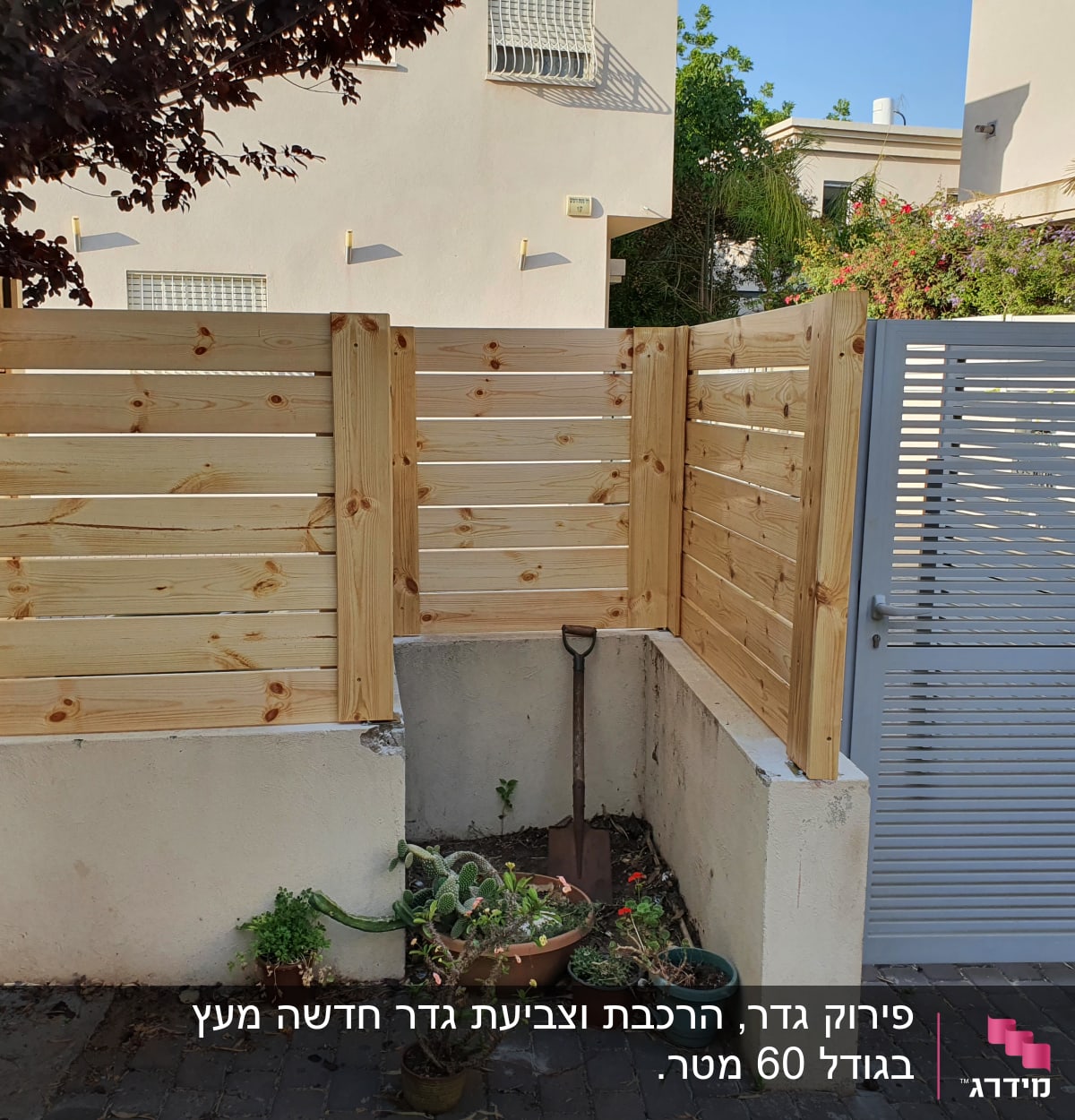 גדר עץ חדשה ליד שער מתכת בגינה